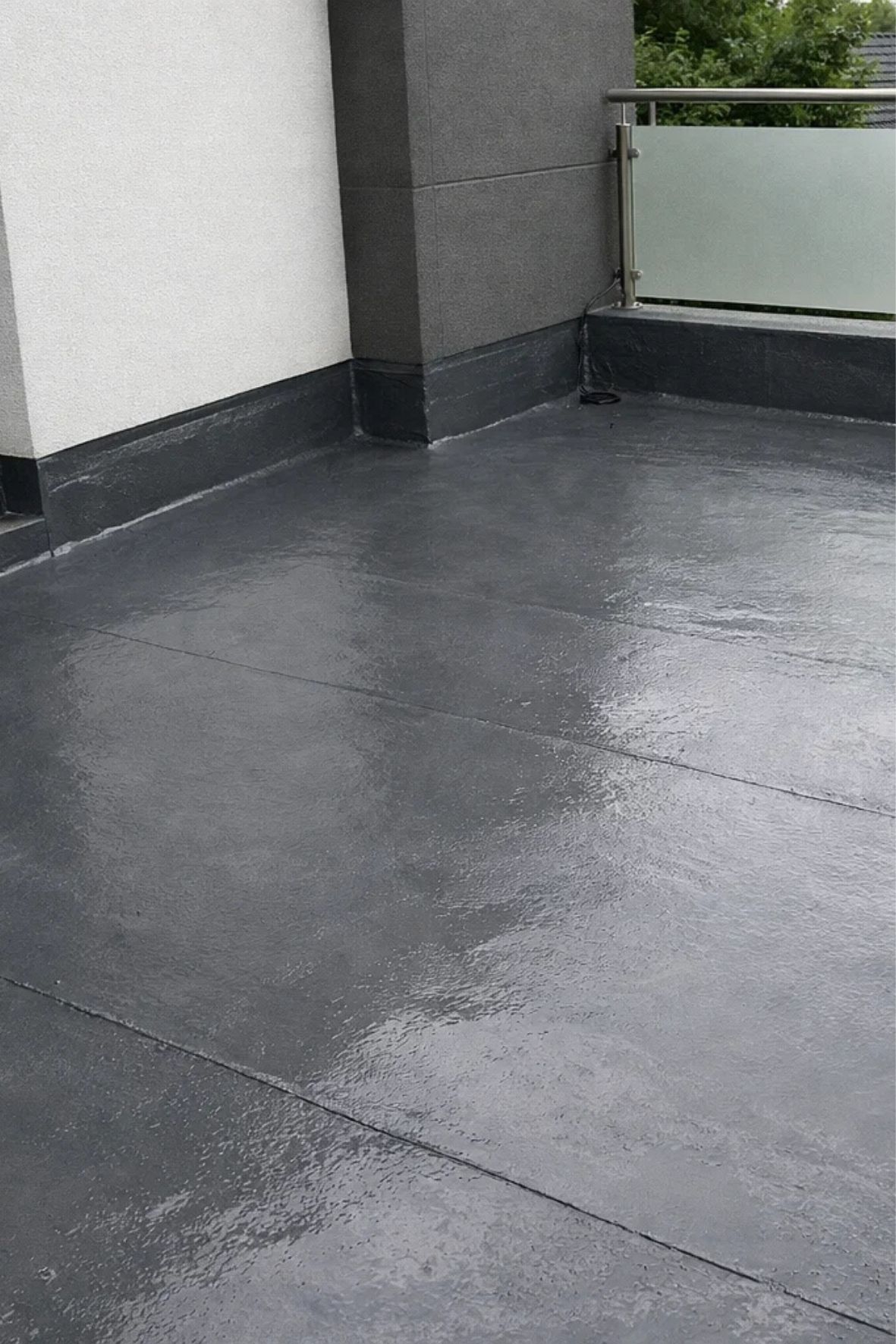 Application manuelle d’un revêtement sombre et uniforme sur une surface extérieure en béton, dans un contexte résidentiel pour bâtiments à L'Ancienne-Lorette